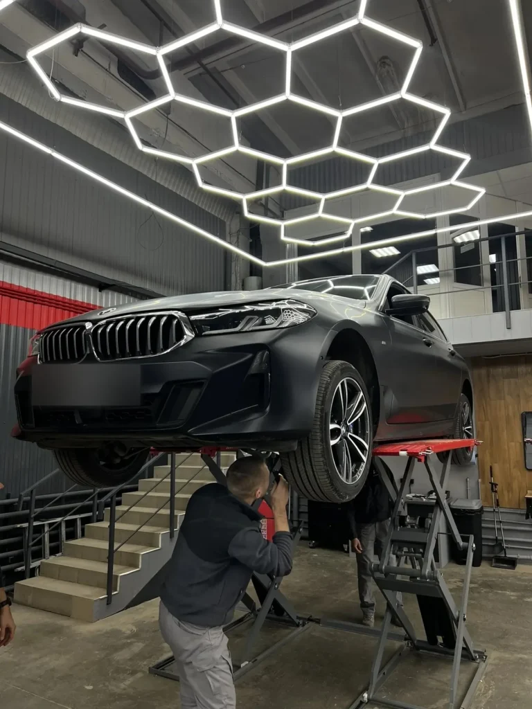 Эксперт АвтоВердикт осматривает днище BMW на подъёмнике, вид спереди