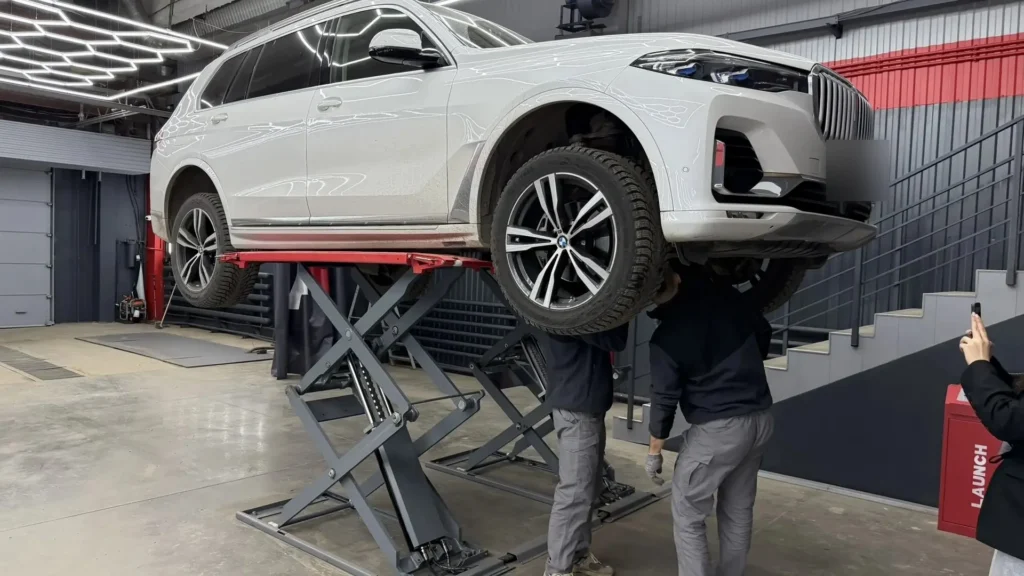 BMW X7 на подъёмнике в центре АвтоВердикт, эксперты осматривают днище